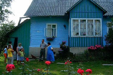 Na tle czerwonych róż stara zamieszkała nadal chata #rodzina #dom #domek #zabytek #StaraChata #chatka #ogród #kwiaty